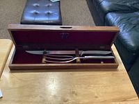 Knife and fork in red-lined wooden case sitting open on table