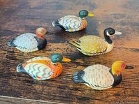 Top view of five painted resin duck figurines on wooden surface