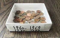 top view of box labeled 1960–1969, 1970–1979 showing loose pennies