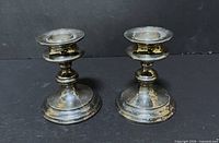 Front view of both candlesticks showing design and tarnish