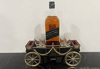 front view of carriage music box bar with shot glasses and example bottle