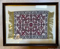 Full view of framed embroidered rug within wood frame