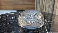 Full view of domed clear crystal paperweight showing snowflake design