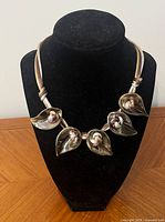 Full view of necklace on display bust showing ribbon cords and five leaf pendants