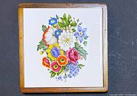 Front of square floral tile trivet in wood frame
