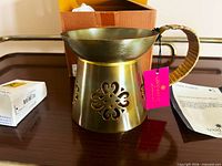 Front view of hammered brass Lama Fumer with handle, oil box and tag visible
