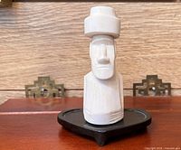Front view of white onyx Moai statue on black wood base