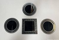 Front view of three round and one square mirrored pieces showing silver Greek key borders