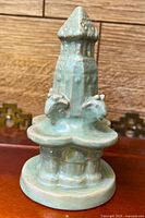 Front view of celadon fountain figurine showing tower, two Capricorn heads, basin and base