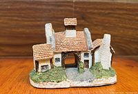 Front view of Lilliput Lane cottage figurine showing arched entrance, tiled roof, garden base