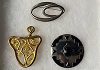 Front view of three brooches showing designs and finishes