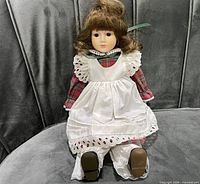 Full view of Schmid porcelain musical doll seated on couch