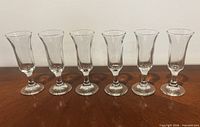Front view of six clear sherry glasses aligned on table