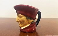 Side profile left of porcelain Toby jug showing cardinal hat and facial details