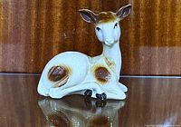 Front angled view of porcelain resting doe deer figurine showing head, body and glazed finish