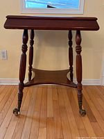 Front view of solid wood side table showing turned legs and lower stretcher shelf