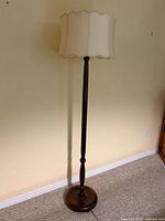 Full view of lamp showing wooden base, pole, and fabric shade