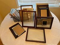 Group of assorted frames on round table with wire basket