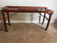 Full view of wooden wash rack on casters against wall