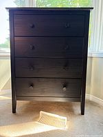 Front view of black 4-drawer chest showing overall design and knobs