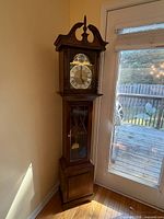Full view of wooden grandfather clock beside door