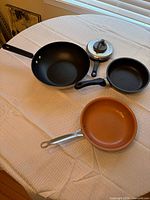 Overall view of assorted pans and lid on table