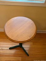 Full view of round wooden side table in front of window