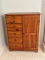 Front view of chest showing six drawers and closed cabinet door
