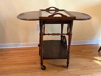 Cart with both leaves raised showing glass tray on top, wheels and shelf visible