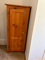 Front view of tall narrow pine cabinet, door closed