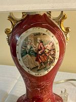 Front view of porcelain lamp base showing courting scene, burgundy glaze, gold accents