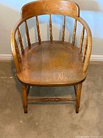 Front view of solid wood Windsor armchair showing spindle back, curved armrests, finish wear.