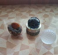 Three paperweights side by side: agate geode half, glass sphere on metal stand, frosted dimpled sphere