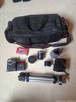 All items laid out: bag, tripod, tape, filter kit, lens, hood, pouches