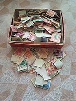 open box filled with loose stamps, some spilled out
