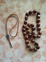 Bolo tie and kukui nut necklace side by side
