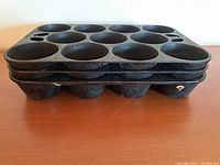 Side view showing three stacked cast iron muffin trays