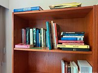Two shelves of assorted Canadiana books, some stacked horizontally