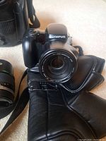 Front view of Olympus IS-3 DLX camera with integrated lens and gloves in foreground