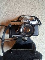 Front angled view of Olympus OM-2 with F.Zuiko 50 mm lens in leather case