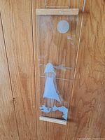 Full view of vertical plexiglass art with wooden rails and wire hanger