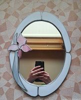 Front view of oval stained glass mirror showing border and flower accent