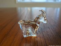 Side profile of clear faceted crystal goat figurine showing horns, body and tail details