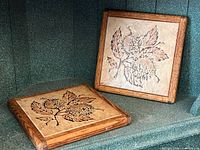 Both square tile trivets showing floral design and wood frames