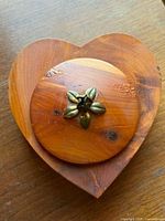 Top view of heart-shaped wooden trinket box with round lid and metal floral knob