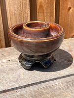 Side view of brown glazed porcelain insulator on wood surface