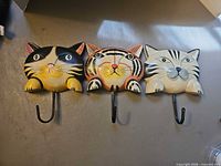 Front view showing three cat face plaques with hooks