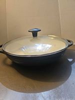 Side view showing pan profile, glass lid, knob, enamel exterior