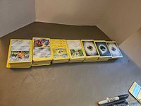 Stacks of yellow-border Pokémon cards including creatures and Energy cards
