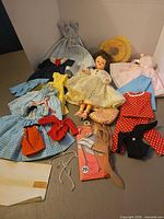 Group shot of doll, multiple dresses, hat, purse, stockings and accessories